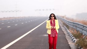 HD Video : Tracking shot of young Indian women walking on Highway Road and enjoying nature during early in the morning.         
