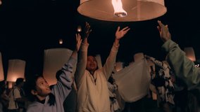 Asian family mother and two daughters releasing hot air paper lantern up to the sky in Yi Peng Lanna ceremony together. Traditional Loy Krathong festivities celebration at night. Slow motion shot. - Powered by Shutterstock - Get 15% off with code: PIKWIZARD15