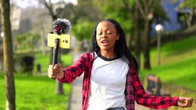 Young african woman recording a video with a mobile phone in an urban park in the city