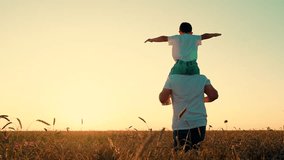 Little kid superhero imagines soaring through sky at sunset. Loving father runs with playful son on shoulders through wheat field. Happy child daydreams about pilot gliding in golden glow of sunset - Powered by Shutterstock - Get 15% off with code: PIKWIZARD15