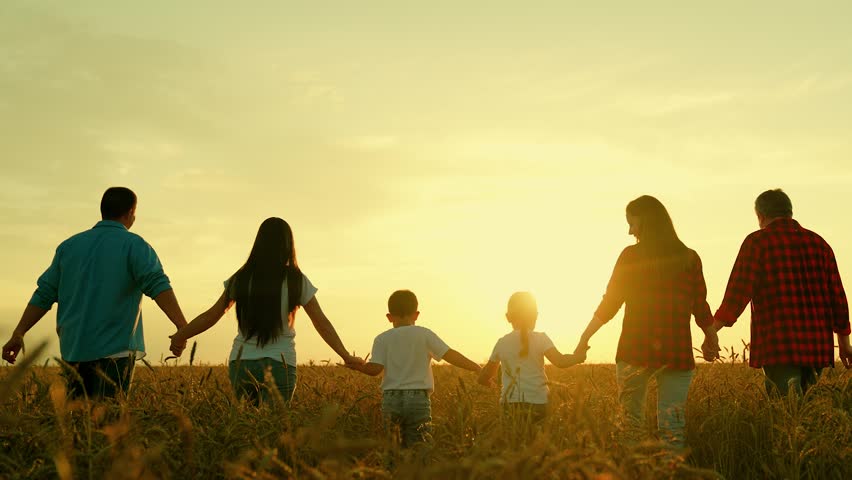 Happy big family walk wheat field, hold hands. Family parents children traveling. Group people go on field at sunset. Group of people united by team idea. Mom, dad, child go for walk together, sunset.