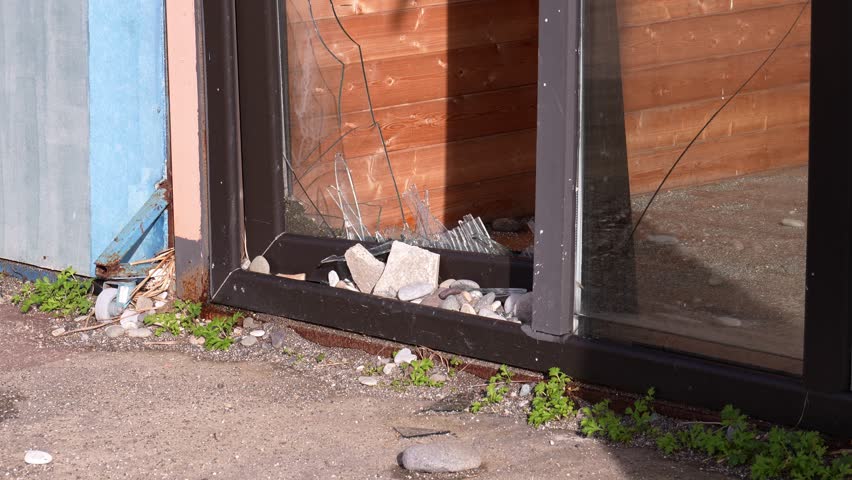 Broken glass in door or window on city street. Vandalism or theft from apartment, house or shop. Street riots. Bandis robbed store. Elements and strong hurricane with wind damaged facade of building. Royalty-Free Stock Footage #3431369521