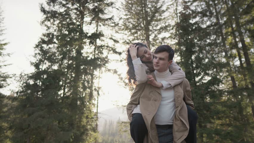 Couple at each other against background century-old trees creates picture moment happiness in nature. A girl on her boyfriend