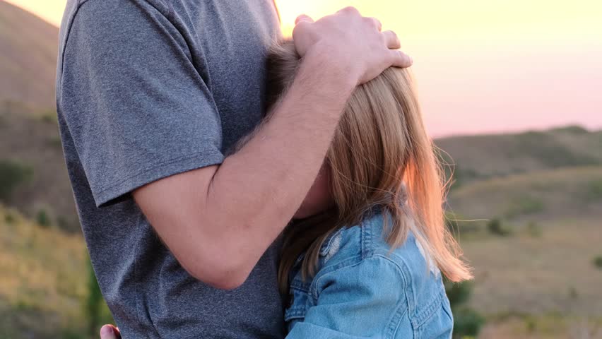 Dad caresses his daughter against the backdrop of the sunset sky. Royalty-Free Stock Footage #3431472763