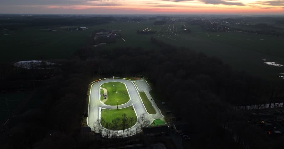 Night time view on a ice skating oval track in Doorn, the Netherlands. Natural ice forming in winter time. Recreational sports event facility. Birds eye aerial view.