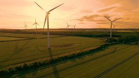 AERIAL, SILHOUETTE: Spinning wind turbines in stunning golden evening light. Picturesque countryside in Northumberland with tall wind powered structures, that provide electricity in a sustainable way - Powered by Shutterstock - Get 15% off with code: PIKWIZARD15