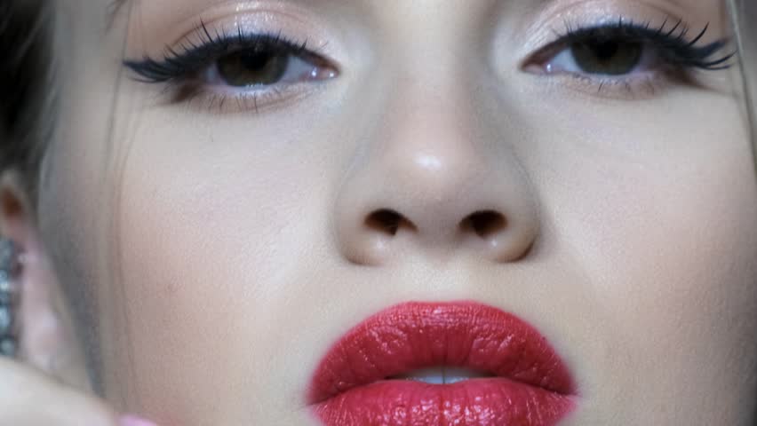 Slow motion video of beautiful young woman face. Female with long earring with rhinestones is in the ear.
