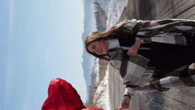 A couple in love is having a romantic date while traveling. A man and a woman are posing against the backdrop of snowy mountains, drinking tea. Travel concept. Vertical video