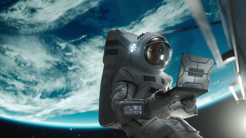 Young Astronaut Floating in Space in Zero Gravity. Spaceman Using a Laptop Computer in Open Space Outside an Orbiting Spacecraft, Browsing Instruction Manuals for Maintenance Work on a Satellite