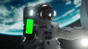 Young Astronaut Floating in Space in Zero Gravity. Spaceman Showing a Smartphone with Green Screen Mock Up Template. Male in a Spacesuit Posing for Camera, Smiling in Open Space Outside an Spacecraft - Powered by Shutterstock - Get 15% off with code: PIKWIZARD15