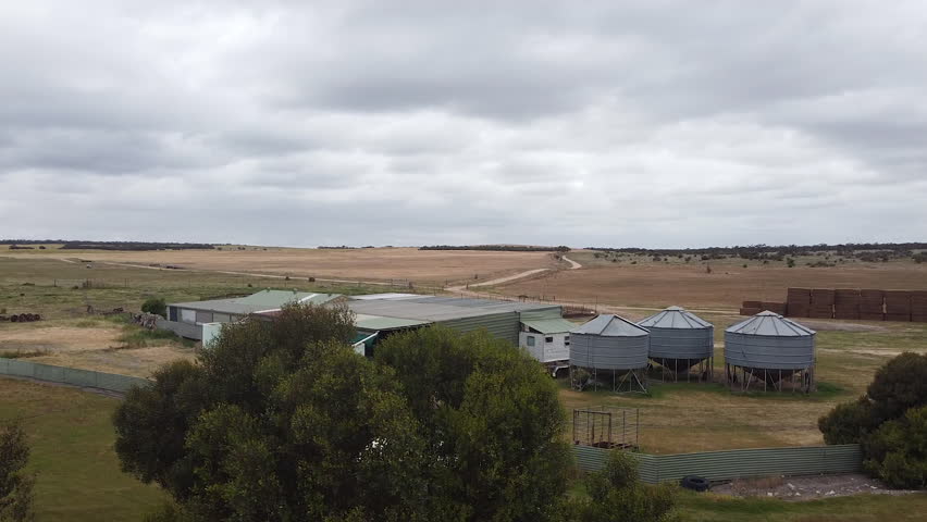 A small grain silo next to a harvest shed on a farm. Drone view. Royalty-Free Stock Footage #3431993055