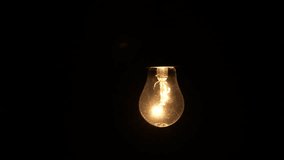 Incandescent bulb turns on and off and flickers on black background, close-up. Warm flashing filament. Glass old lightbulb glowing yellow warm light. Tungsten lamp light, 4k - Powered by Shutterstock - Get 15% off with code: PIKWIZARD15