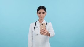 Female doctor or nurse talking on a video call with phone over blue background