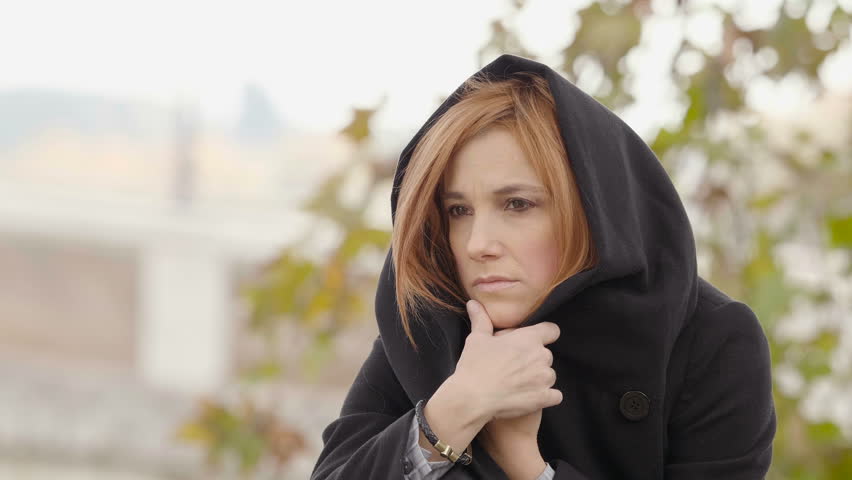 depressed, sad and cold woman protects herself in her warm coat
