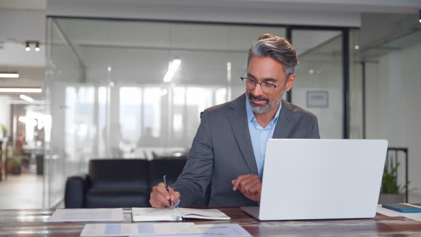 Middle-age Hispanic man using laptop computer for business studying, watch online virtual webinar training meeting, video call. Focused mature Indian or Latin businessman work in office, copy space. Royalty-Free Stock Footage #3432134889