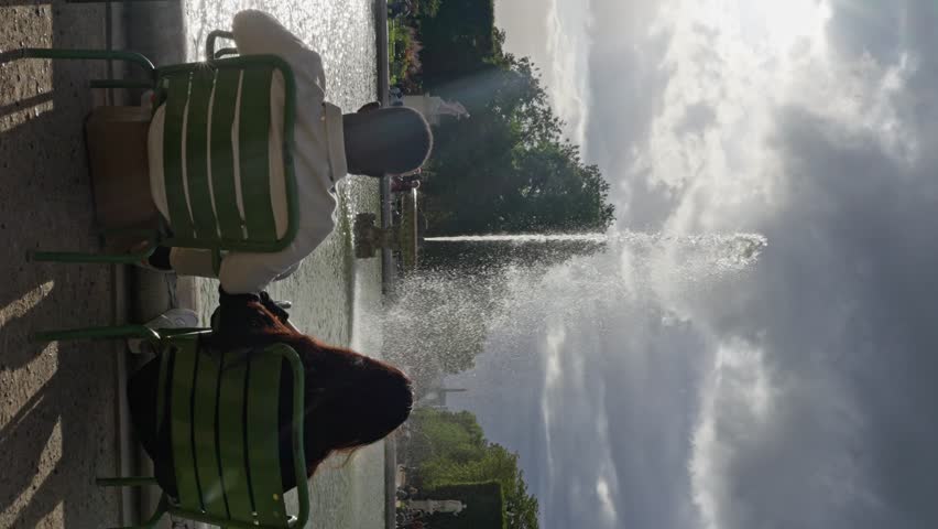 Multi-ethnic People Sitting in Front of Fountain at the Jardin des Tuileries. a couple of lovers sits in front of a fountain in France, a man and a woman look at the fountain in the park,