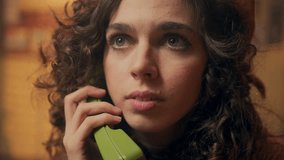 Bad news for attractive young woman in a yellow retro beret is talking on the phone and is upset. A curly-haired girl in a vintage office is crying because of news on a wired telephone.