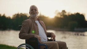 Senior man in wheelchair enjoys freedom. Male with special need look at the camera smiling breathing fresh air walking in city park near nature. Living with physical disability in old age concept. - Powered by Shutterstock - Get 15% off with code: PIKWIZARD15