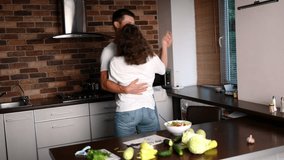 Happy young couple smiling, dancing, kissing in the kitchen while preparing dinner. Man and woman in love having fun while preparing food, feeling happy together.Concept of cooking food at home, love. - Powered by Shutterstock - Get 15% off with code: PIKWIZARD15