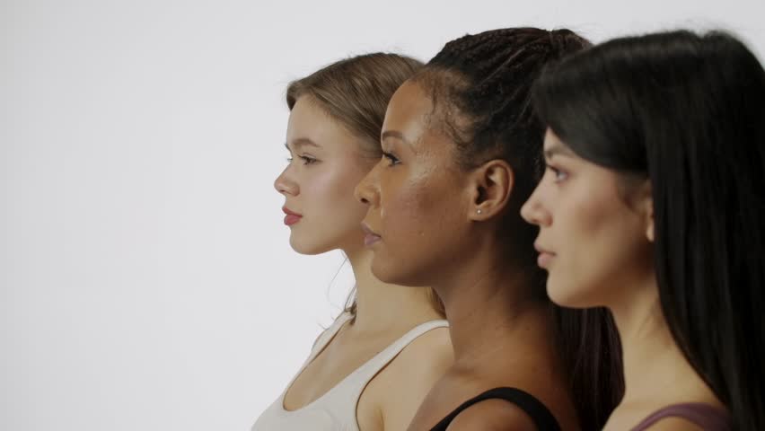 Portrait of multiethnic female models isolated on white background, face close shot. Group of three young multiracial girls pose at the camera. Multiethnic beauty concept.