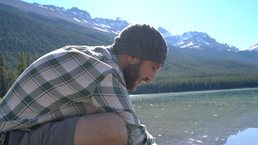 Caucasian male drinking fresh water from mountain lake in Banff national park, Alberta, Canada. People travel nature environment concept- 4K