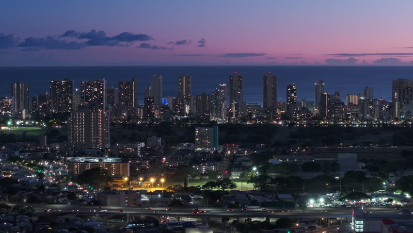 Drone flying along ocean front resorts on Waikiki at sunset. Cinematic aerial above Honolulu, Hawaii USA. Scenic pink purple sunset sky above city illuminated at night. Modern cityscape of Oahu island Royalty-Free Stock Footage #3432295735