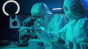 Scientists in protection suits and masks working in research lab using laboratory equipment: microscopes, test tubes. Medicine, coronavirus 2019-ncov infection and vaccine discovery. - Powered by Shutterstock - Get 15% off with code: PIKWIZARD15