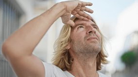 Blond man shielding eyes from sun on city street - Powered by Shutterstock - Get 15% off with code: PIKWIZARD15
