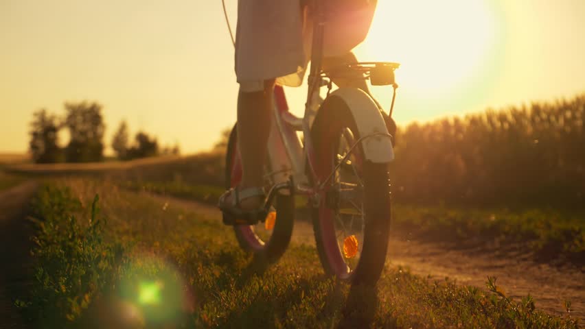 happy family in the park. Little girl rides a bicycle. The child's feet are pedaling. The kid is riding at sunset, spinning a bicycle wheel. A chidhood dream. Physical activity, cardio. Royalty-Free Stock Footage #3432328309