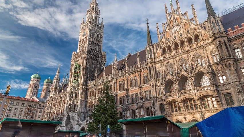 Marienplazt Old Town Square with the New Town Hall timelapse. Neues Rathaus and Town Hall Clock Tower Glockenspiel. Munich skyline, downtown cityscape with clouds on a blue sky. Bavaria, Germany