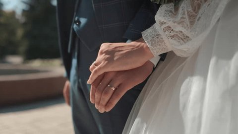 handsome groom businessman in a jacket touches his hands close-up to the bride in a white dress during a wedding walk, wedding day, details Arkivvideo