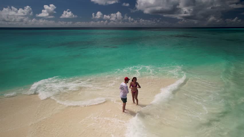Couple stand on white sandbar, aerial view turn around cayo de agua island people enjoy daybeach