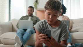Gadget addicted family with devices at home multiracial mom and dad using laptops addict work ignoring sad child little boy son bored kid with phone smartphone on floor lack parents attention custody - Powered by Shutterstock - Get 15% off with code: PIKWIZARD15