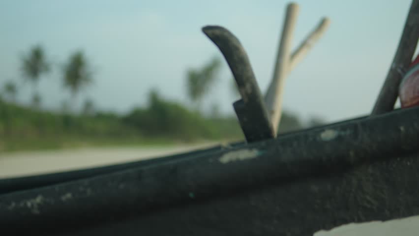 Close-up of a stranded boat with blurry greenery and beach in the background