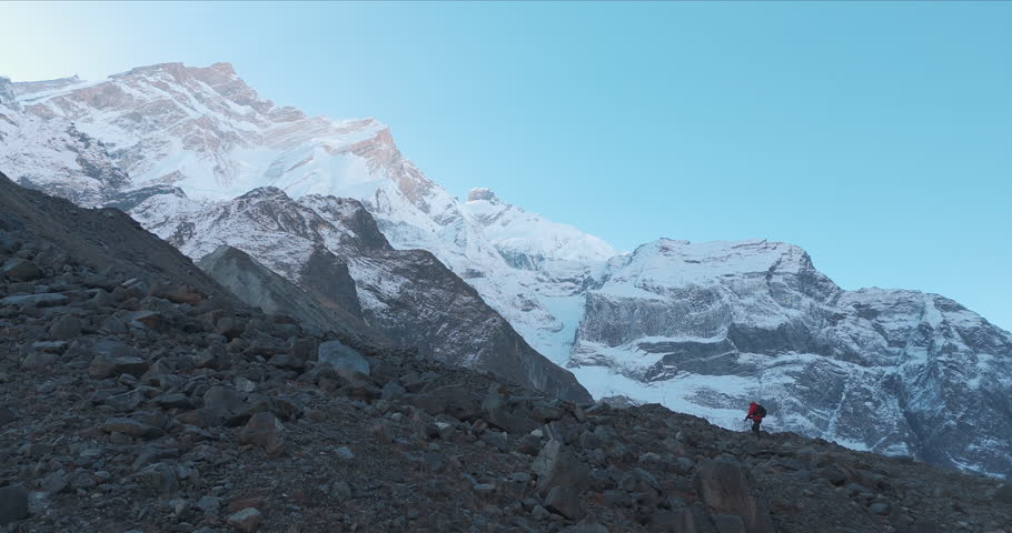 A male tourist treks upward mountain range Nepal, the World's highest peak Mount Everest, tough trails, sunlight, snow, and landscape drone shot peaceful cinematic 4K Royalty-Free Stock Footage #3432433597