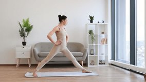 Mature brunette practising Warrior I Halfway Fold during yoga exercise at home. Caucasian woman spread her legs wide and pulls one knee forward, straightening arms up above the head. - Powered by Shutterstock - Get 15% off with code: PIKWIZARD15