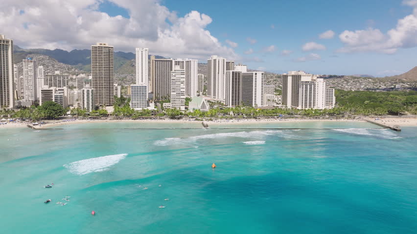 Impressive travel destination copy background. Breathtaking views on delight light teal blue ocean at Waikiki beach. Modern city at blue sea with green mountains on background. Honolulu city aerial 4K Royalty-Free Stock Footage #3432511581