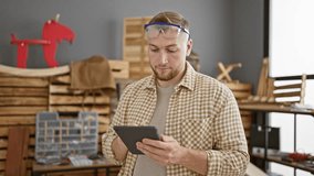 Handsome bearded man in safety glasses using tablet in a woodwork workshop. - Powered by Shutterstock - Get 15% off with code: PIKWIZARD15