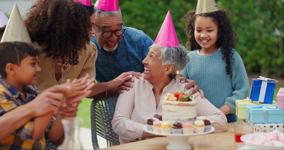 Senior woman, birthday cake and family in garden with applause, celebration and happy together for party. Man, women and children in grandparents backyard with present, dessert and love in summer Royalty-Free Stock Footage #3432579213