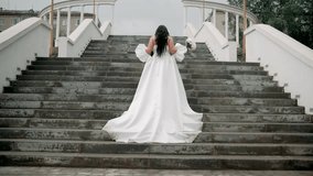 a bride in a white dress with a train climbs the stairs, view from the back, general plan - Powered by Shutterstock - Get 15% off with code: PIKWIZARD15