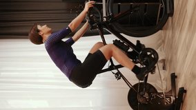 Woman is cycling on smart trainer. Female cyclist is spinning on stationary exercise bike. Indoor cycling. Vertical video