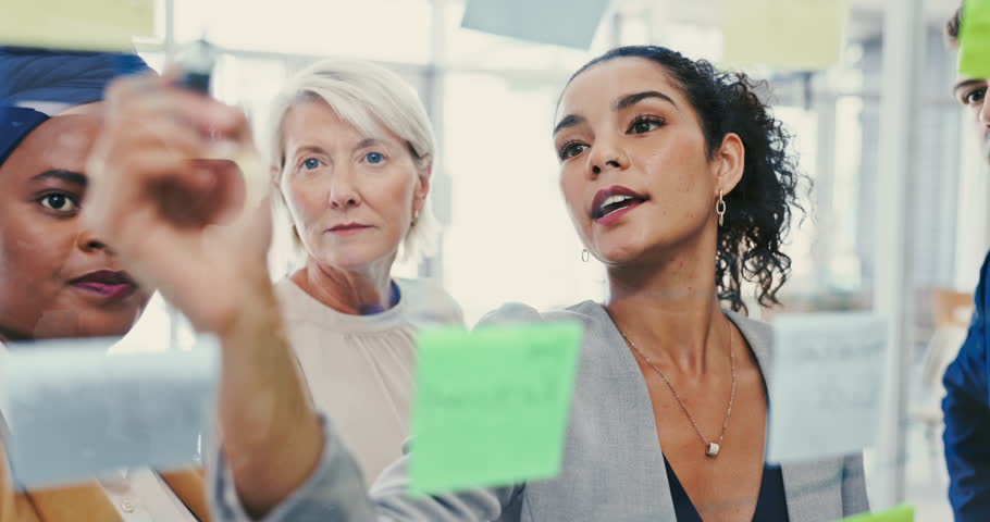 Meeting, writing and sticky note with business woman talking to team in office for vision development. Collaboration, coaching and glass with employee group in workplace for game plan discussion