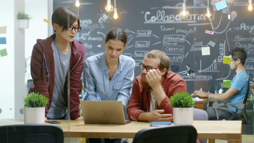 Three Creative People Have Active Discussion About Ongoing Project While Using Laptop. Stylish Young People Work in Trendy Environment. Shot on RED EPIC-W 8K Helium Cinema Camera. Royalty-Free Stock Footage #34327756