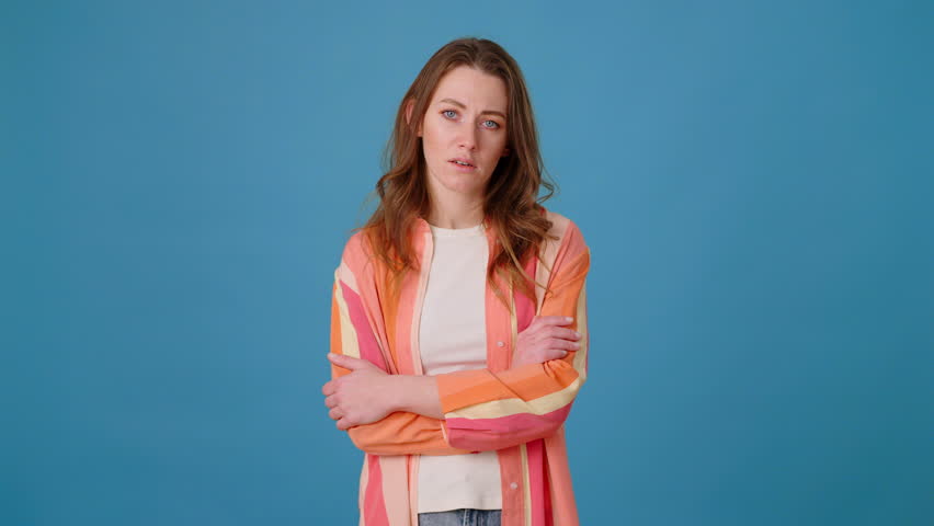 Upset lady in bright shirt rubs temples in hope headache goes away in light premise. Woman writhing in pain against blue wall. Disease in upper part of head Royalty-Free Stock Footage #3432837649