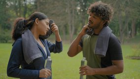Tired exhausted Indian man and woman relaxing after sports in park outdoor Arabian fitness couple in city sport people wipe sweat with towels exhausted relax pause break drinking bottled water refresh - Powered by Shutterstock - Get 15% off with code: PIKWIZARD15