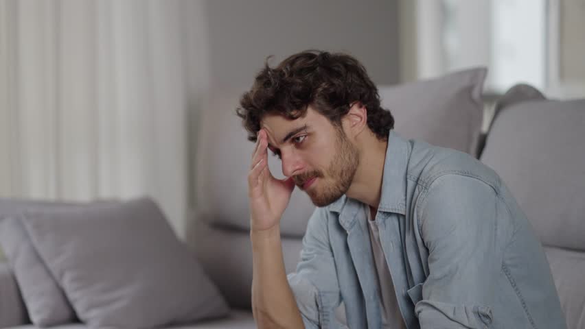 Disappointed young man sitting on couch thinking looking out the window feels moral badly after quarrel fight with wife, break up or divorce marriage split, unpleasant events in life suffering concept Royalty-Free Stock Footage #3432905171