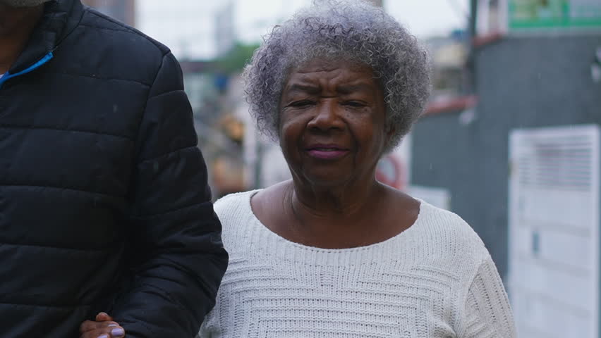 Genuine Family Care - African American Man in 50s and His 80-Year-Old Mother Walking Together in City conversing, Embodying Love and Support in Senior Years Royalty-Free Stock Footage #3432933195