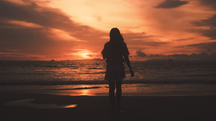 Lonely girl in the shadow of the ocean. Silhouette of girl standing.