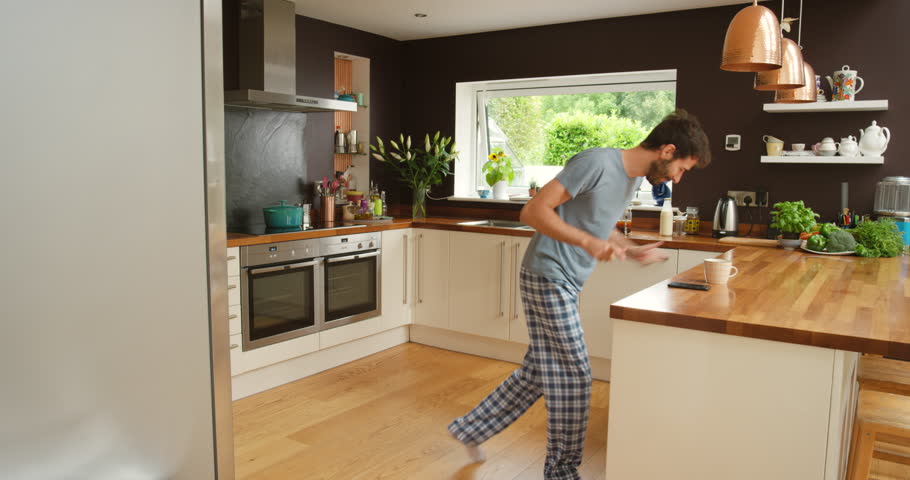 Man, dancing and happy in kitchen for coffee, relax and streaming podcast on weekend in modern home. Person, cappuccino and tea break on mobile app for music, espresso and online radio for morning