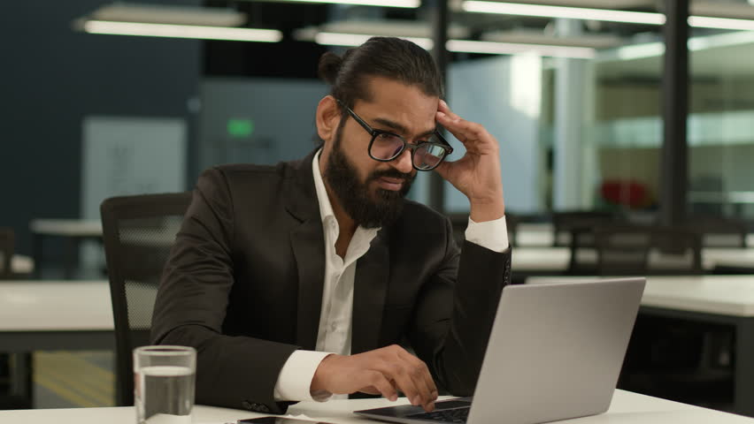 Bored Arabian business man at office table tired Indian clerk businessman worker sad dissatisfied disinterest manager employer boredom at workplace indoors laptop computer typing exhausted boring job Royalty-Free Stock Footage #3432980153
